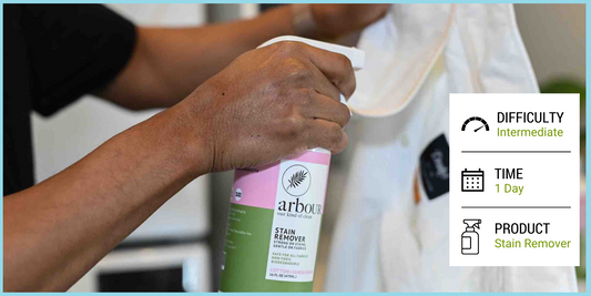 A man spraying stain remover on a white collared shirt