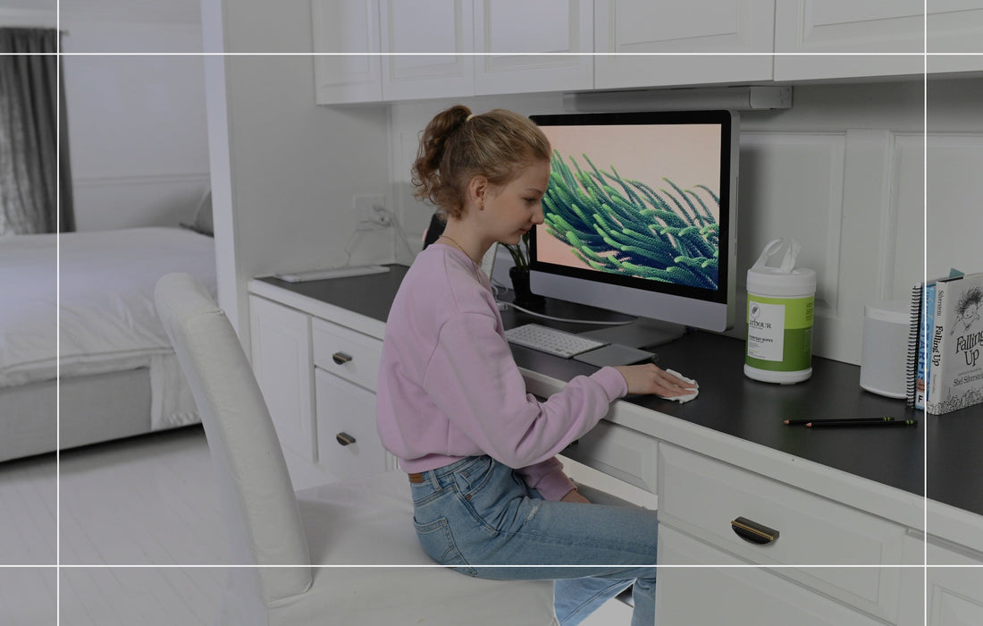 Young girl using arbOUR Everyday Wipes to clean computer desk